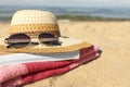 Hat, sunglasses, book and striped towel on sandy beach near sea, closeup. Space for text Royalty Free Stock Photo