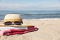 Hat, sunglasses, book and striped towel on sandy beach near sea, closeup. Space for text Royalty Free Stock Photo