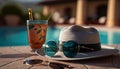 a hat, sunglasses, and a drink sitting on a table next to a pool. Royalty Free Stock Photo