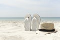 Hat and white flip-flops on the beach with blue sea in the background Royalty Free Stock Photo