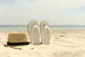 Hat and white flip-flops on the beach with blue sea in the background Royalty Free Stock Photo