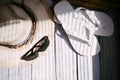 A hat, white flip flops, sunglasses, a beach bag on the white wooden background, hard light