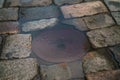 Hatch in puddle on old stone pavement background Royalty Free Stock Photo