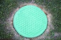 The hatch is round cast iron turquoise with a pattern of many small turquoise rings on a green grass background Royalty Free Stock Photo