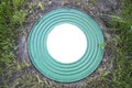 Hatch well cast iron heavy turquoise with a pattern of many rings on a background of green grass. In the center of the round white Royalty Free Stock Photo