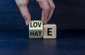 From hate to love symbol. Hand turns the cube and changes the word `hate` to `love`. Beautiful dark wooden background, copy sp