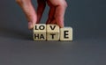 From hate to love symbol. Hand turns cubes and changes the word `hate` to `love`. Beautiful grey background, copy space.