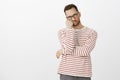 Hate waiting in queues. Portrait of annoyed tired handsome guy with bristle in black eyewear, leaning face on hand and Royalty Free Stock Photo