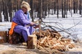 Hatgal, Mongolia, Febrary 25, 2018: Smiling mongolian man wears traditional costume is cutting wood with axe outdoors Royalty Free Stock Photo