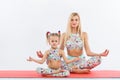 Hatha yoga fitness . Young mother and daughter exercise together indoors. Family look.