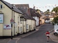 HATHERLEIGH, DEVON, ENGLAND - AUGUST 9 2022: View along Bridge St with cottages, bunting flags, and a young man on a