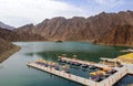 Beautiful deep green Hatta lake between Hajar Mountains with many kayaks and boats for rent