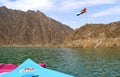 United Arab Emirates flag waving on top of a hill in the Middle of Hatta lake with two colorful kayaks on a foreground