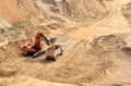 Excavator developing the sand on the opencast and loading it to the heavy dump truck Royalty Free Stock Photo