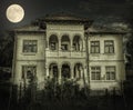 Haunted house with dark horror atmosphere and full moon. Creepy old mansion at night. Spooky scene like in frightening movies. Sty Royalty Free Stock Photo