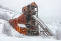 Abandoned coal mine covered in snow with rusty structures and a winter landscape background Royalty Free Stock Photo