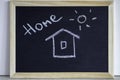 Hause and sun painted with chalk and the inscription home. Wooden chalkboard with picture. Happy, sweet home and family concept.