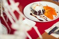 Haute cuisine concept. Ice cream brownie sundae with chocolate sauce and slices of date plum on white plate. Close up. Indoor shot Royalty Free Stock Photo