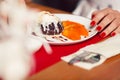 Haute cuisine concept. Woman`s hand with perfect manicure and ice cream brownie sundae with chocolate sauce and slices of date Royalty Free Stock Photo