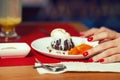 Haute cuisine concept. Woman`s hands with perfect manicure and ice cream brownie sundae with chocolate sauce and slices of date Royalty Free Stock Photo