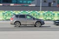 Haval H6 SUV in motion. Gray dirty crossover is fast driving on city street. Side view of car rushing on urban road