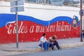 HAVANA, CUBA - APRIL 2, 2012:Cuban teenagers sitting near propaganda graffiti