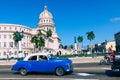 HAVANA, CUBA - DECEMBER 10, 2019: Brightly colored classic American cars serving as taxis pass on the main street in front of the Royalty Free Stock Photo