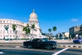 HAVANA, CUBA - DECEMBER 10, 2019: Brightly colored classic American cars serving as taxis pass on the main street in front of the Royalty Free Stock Photo