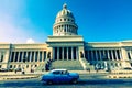 HAVANA, CUBA - DECEMBER 10, 2019: Brightly colored classic American cars serving as taxis pass on the main street in front of the Royalty Free Stock Photo