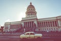 HAVANA, CUBA - DECEMBER 10, 2019: Brightly colored classic American cars serving as taxis pass on the main street in front of the Royalty Free Stock Photo