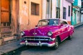 HAVANA, CUBA - DECEMBER 10, 2019: Havana Cuba Classic Cars. Typcal Havana urban scene with colorful buildings and old cars Royalty Free Stock Photo