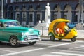 Old car and Cocotaxi in Old Havana. Coco taxi is an auto rickshaw type taxi vehicle in Cuba and a cheap way to go from one point Royalty Free Stock Photo