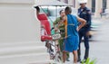 Pedi-taxi rider stands by his taxi talking while uniformed police observe busy street blurred in background