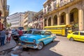 Havana, Cuba - March 11th 2018 - Blue vivid old car in a street of Havana, bus and taxi in the background, colonial buildings. Royalty Free Stock Photo