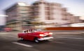 Motion-blurred 1950`s Chevy drives past high rises in Havana, Cu Royalty Free Stock Photo