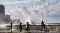 Havana, Cuba - November 19, 2011 - Young men line up on a concrete wall to fish from the bay as waves crash over the