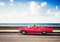 Cuban driver takes a tourist on a city tour in a american red convertible vintage car on the