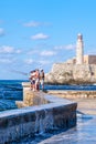 People fishing at the malecon seawall in Havana with El Morro fortress on the background