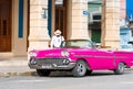 Cuban man on his american pink 1958 Chevrolet classic car convertible in the old town from