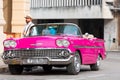 Cuban man on his american pink 1958 Chevrolet classic car convertible in the old town from