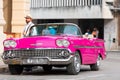 Cuban man on his american pink 1958 Chevrolet Impala 283 Ramjet classic car convertible in the