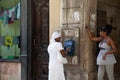 Havana / Cuba - 04.15.2015: Young Cuban woman wearing a Santeria white dress making a phone call on a public phone