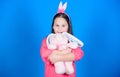 Have blessed Easter. Bunny girl with cute toy on blue background. Child smiling play bunny toy. Happy childhood. Get in