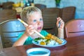 Have a break. Vegetarian food can be delicious for everybody. Boy eat rice and stew vegetables in white plate with Royalty Free Stock Photo