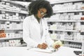 We have a few scheduled pickups today. a focused young female pharmacist making notes while reading the label of a Royalty Free Stock Photo