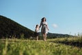 Have fun with child in nature, the joy of motherhood. Young beautiful European mother in blue dress runs through chamomile field