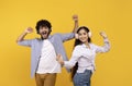 Have fun and enjoy music together. Happy young indian couple dancing in headphones, yellow background Royalty Free Stock Photo