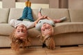 Have fun. Portrait of playful kids, little boy and girl lying upside down on a sofa in the living room