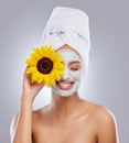 Have fun while taking care of your skin. an attractive young woman wearing a face mask and holding a sunflower over her Royalty Free Stock Photo