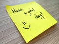 Have a good day handwritten message on yellow sticky note on wooden background